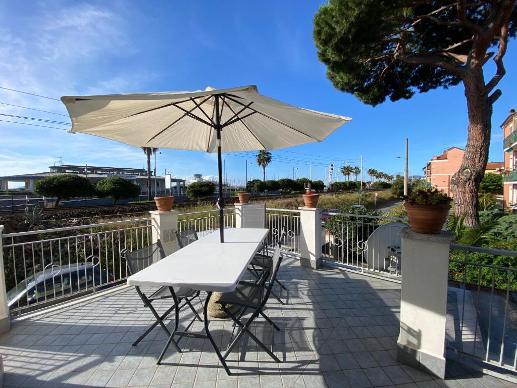 een witte tafel en stoelen met een parasol bij La casa di Carlotta in Loano