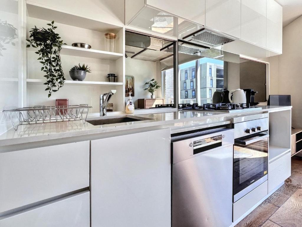 a kitchen with white cabinets and a sink at Beautiful 1B1B Prahran apartment in Melbourne