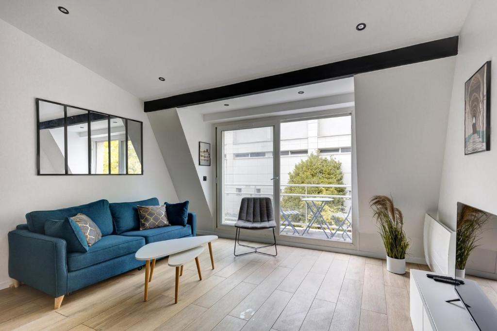 ein Wohnzimmer mit einem blauen Sofa und einem Fenster in der Unterkunft Suite New Delhi - Superbe Appartement in Suresnes