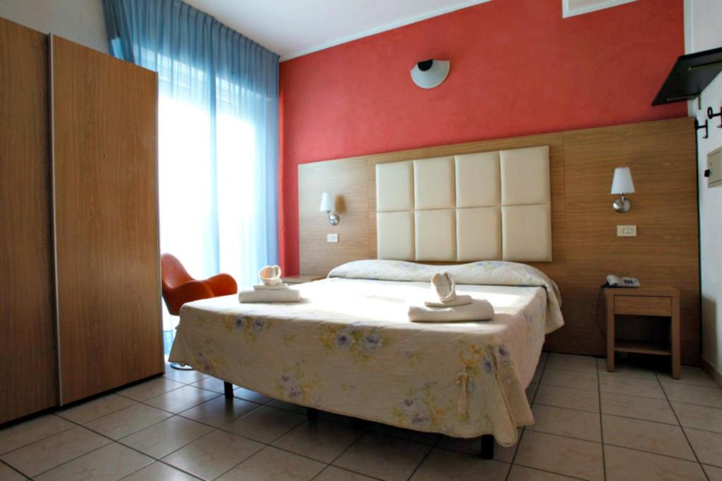 a bedroom with a large bed with a red wall at Hotel Marebello in Rimini