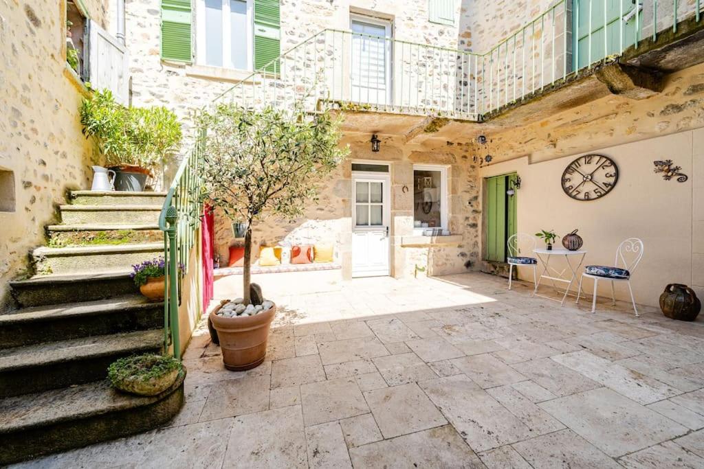 une cour avec des escaliers et une horloge sur le mur dans l'établissement Petit village au calme, à Chadeleuf