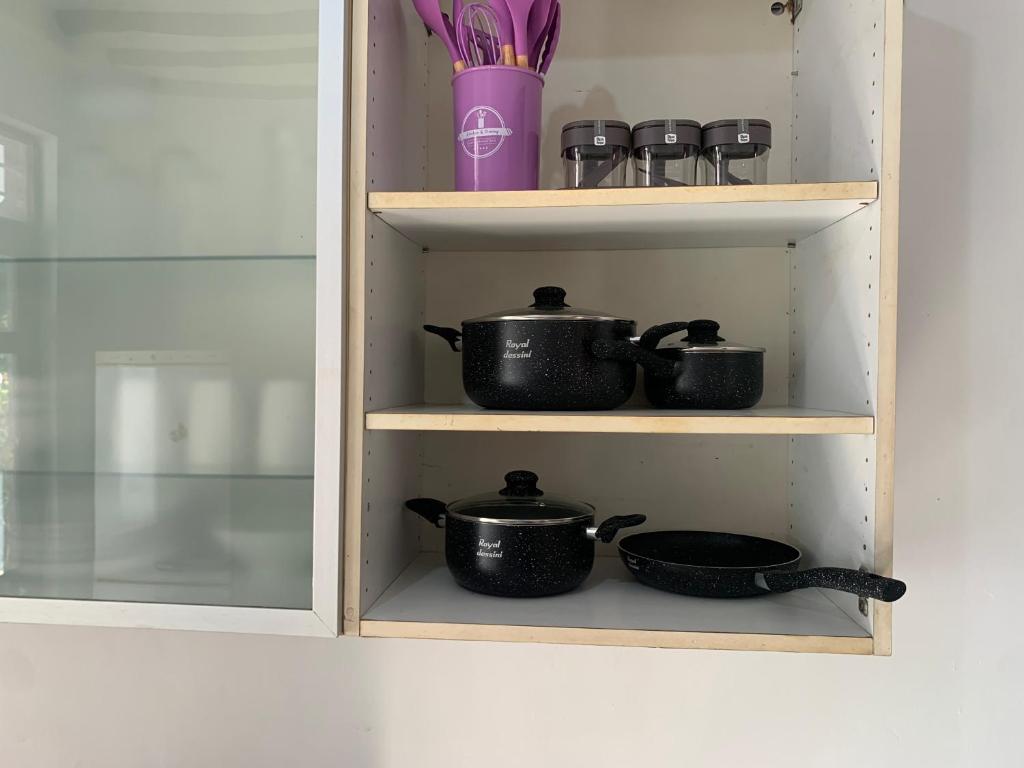 a cabinet with two pots and pans on a shelf at Kisharif holiday home in Makunduchi
