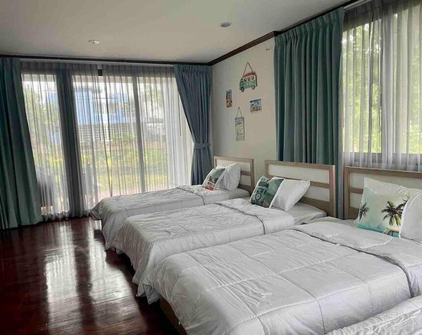 ナ・ジョムティエンにあるSunshine House at Sunset Beachのベッド3台 緑のカーテンが備わる部屋