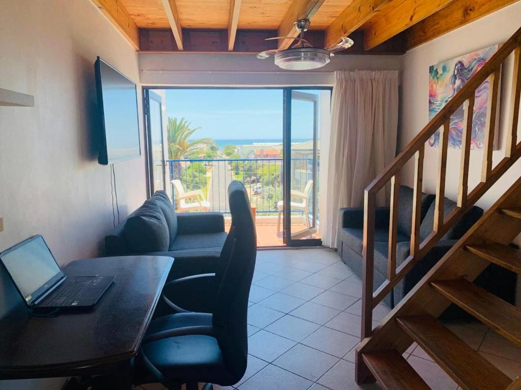 un soggiorno con tavolo e computer portatile su una scrivania di At Sea, Melkbosstrand a Melkbosstrand