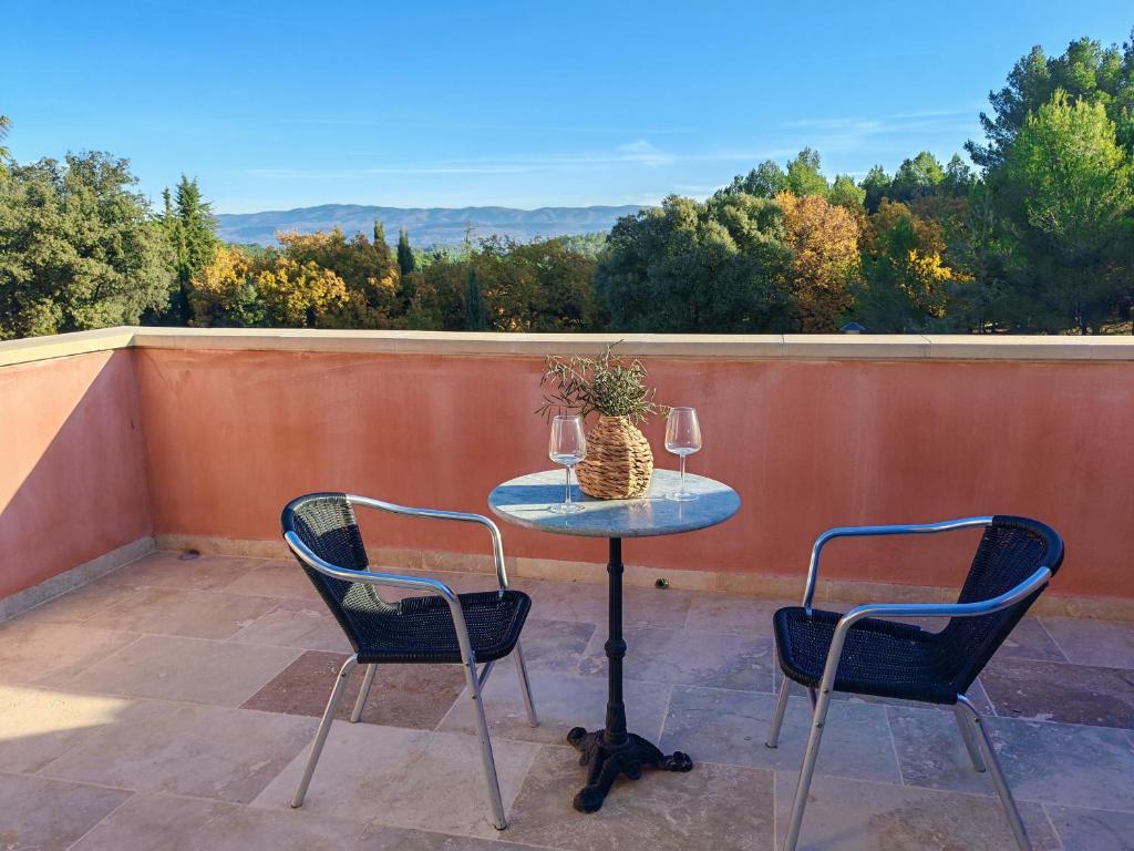 - une table avec deux chaises et deux verres de vin dans l'établissement Les deux Oliviers, à Roussillon
