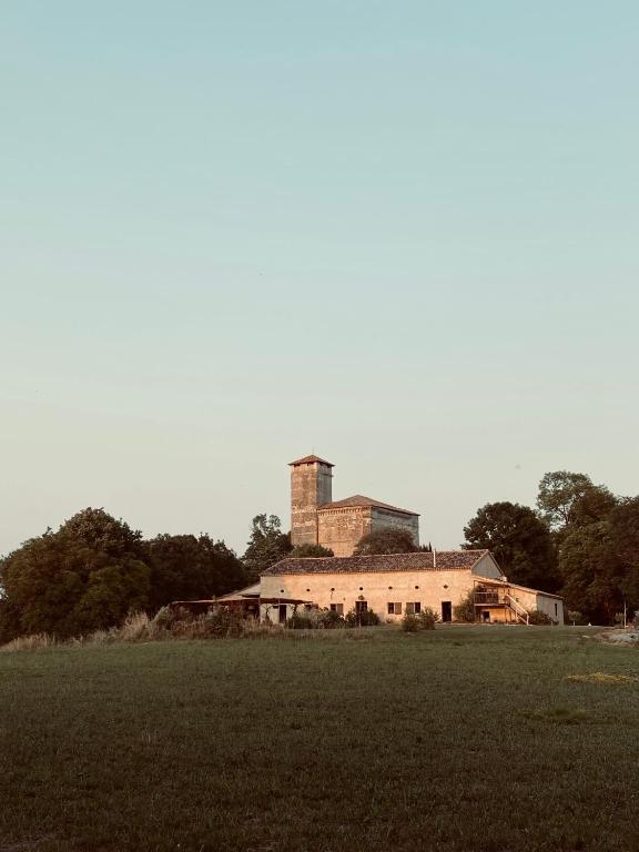 un bâtiment avec une tour au-dessus d'un champ dans l'établissement Maison drôles d'oiseaux, à Plieux