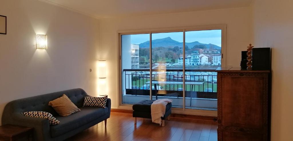 un salon avec un canapé et une grande fenêtre dans l'établissement Grand appartement avec vue - Plage à pied, à Saint-Jean-de-Luz