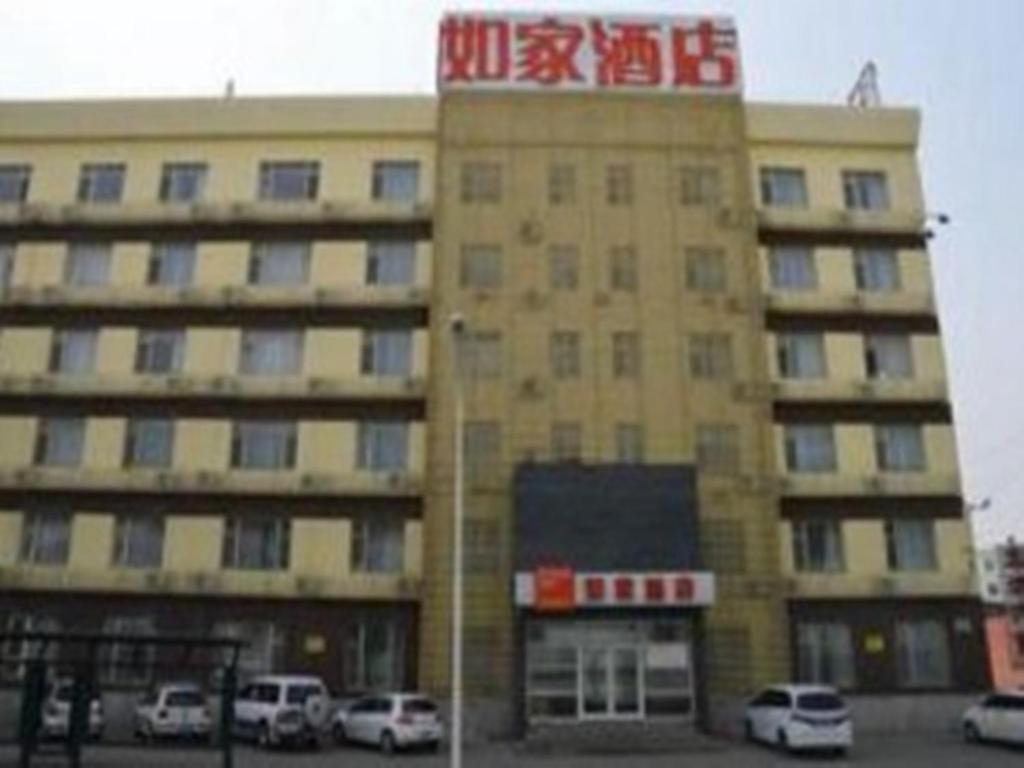 un gran edificio con coches estacionados en un estacionamiento en Home Inn Changchun Qianjin Street Weixing Road, en Changchún