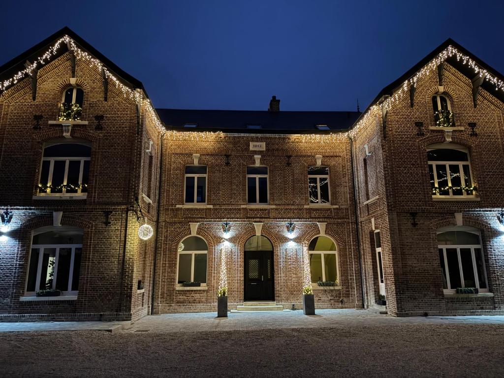 Un viejo edificio de ladrillo con luces por la noche. en Aura Castle, en Picquigny