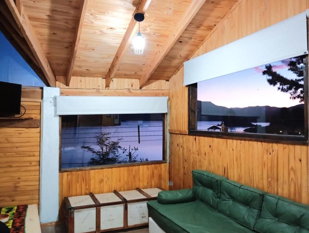 - un salon avec un canapé vert et 2 fenêtres dans l'établissement Patagonia Andina, a metros del lago, excelente vista, à Villa Pehuenia