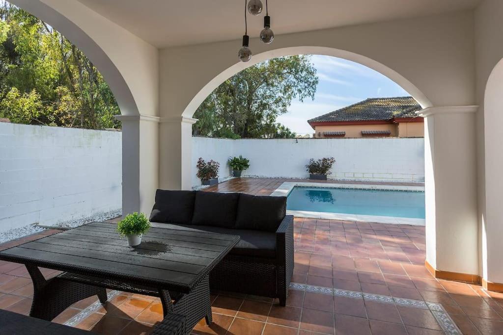 a patio with a couch and a table and a pool at Valdeazahares House in El Puerto de Santa María