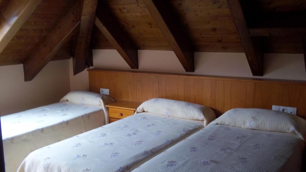 Dos camas en una habitación con techos de madera. en Hostal Pernalle, en Erill la Vall