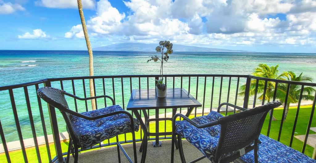 a table and chairs on a balcony with the ocean at Check In, Chill Out - Annies Surf Shack Awaits! in Kahana