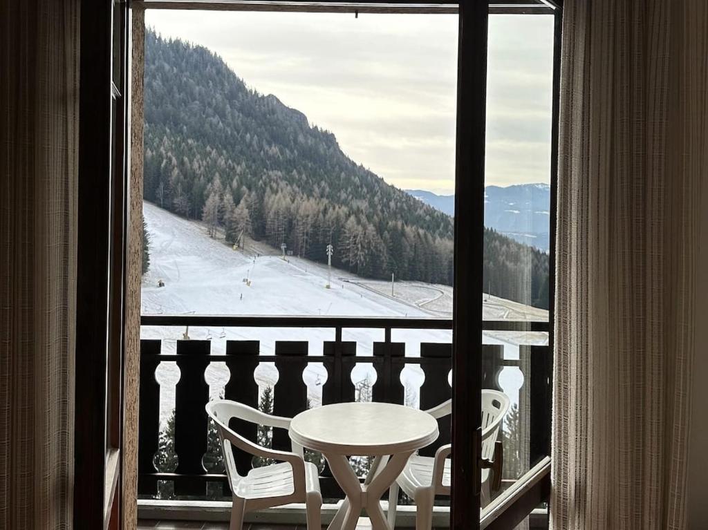 a table and chairs on a balcony with a snow covered mountain at Casa Del Tramonto-Golden House in Dosso