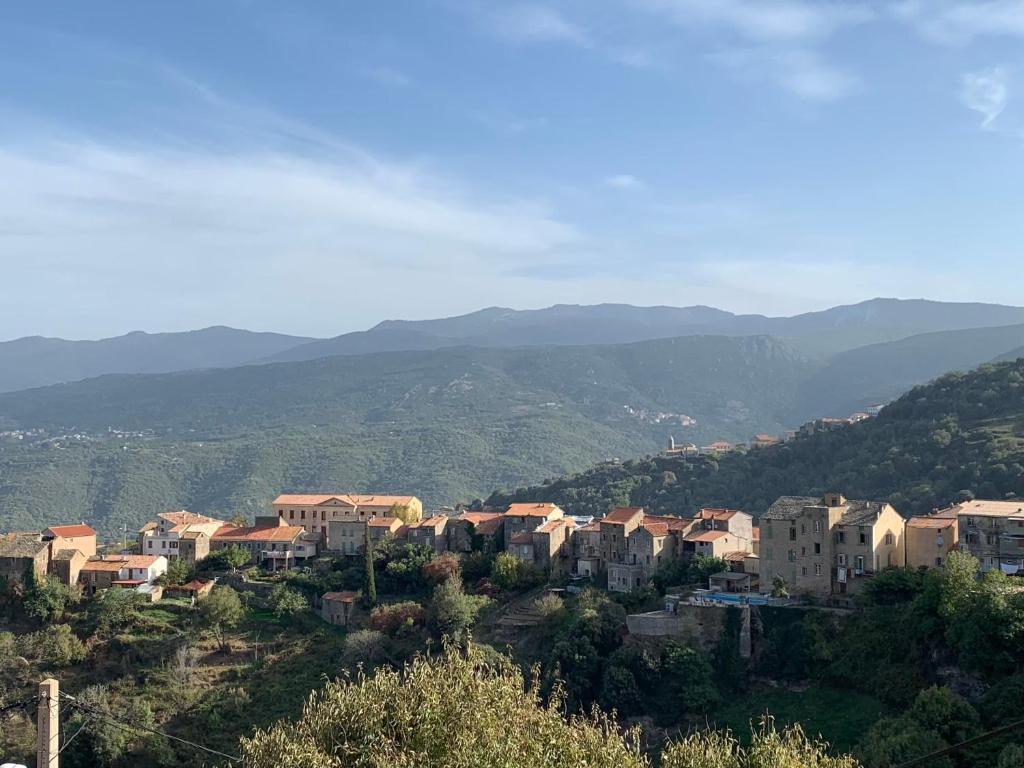 une ville sur une colline avec des montagnes en arrière-plan dans l'établissement Maison indépendante Haute-Corse mer et montagne, à Santo-Pietro-di-Tenda