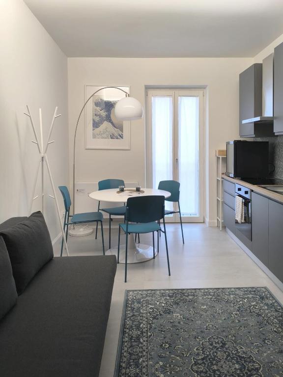a living room with a table and chairs and a kitchen at Appartamento Hokusai in Brescia