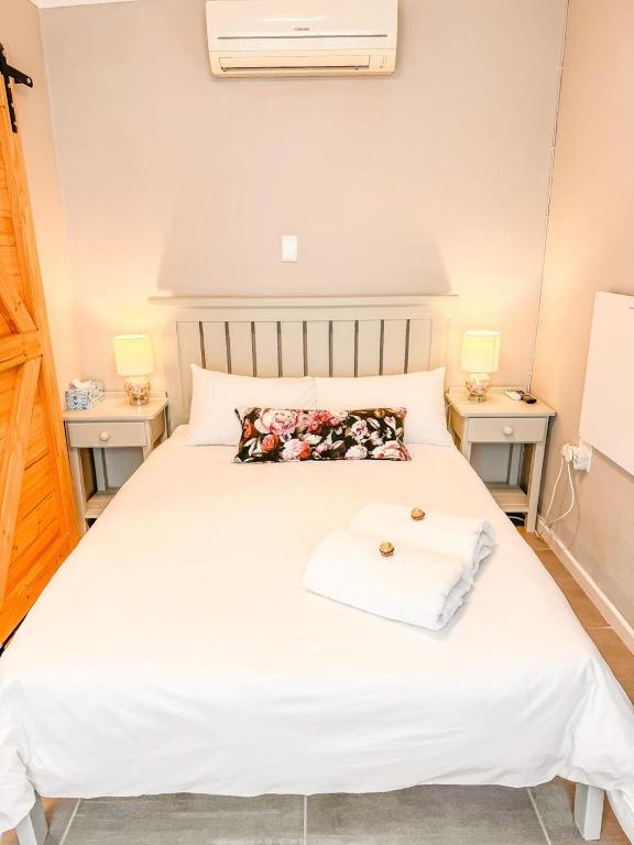 a bedroom with a white bed with two night stands at Vrede Villa - no loadshedding in Beaufort West