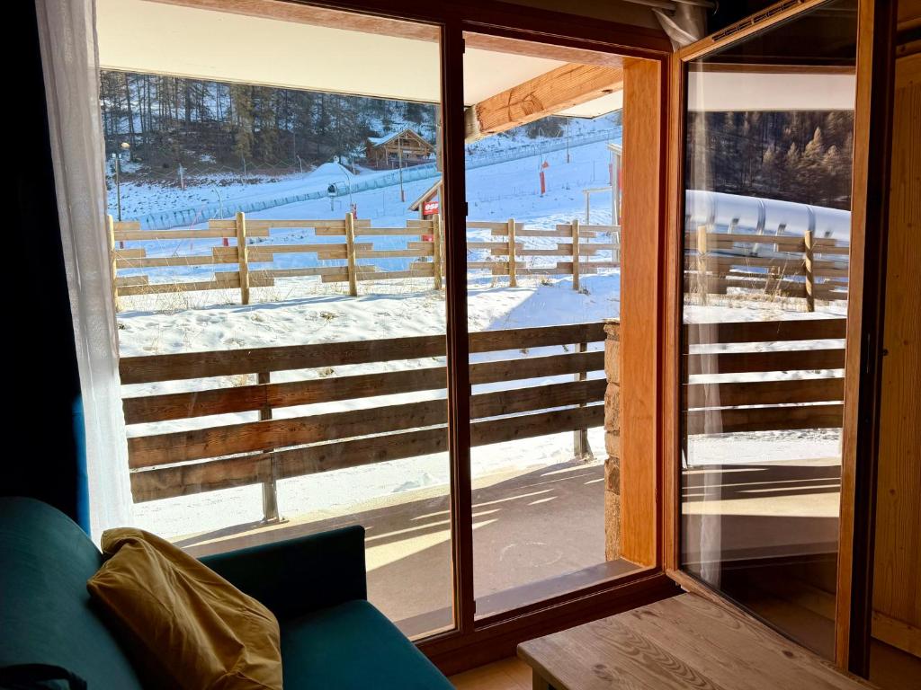 - une vue sur un champ enneigé à travers une fenêtre dans l'établissement Appartement aux Orres 1800 en RDC, aux Orres