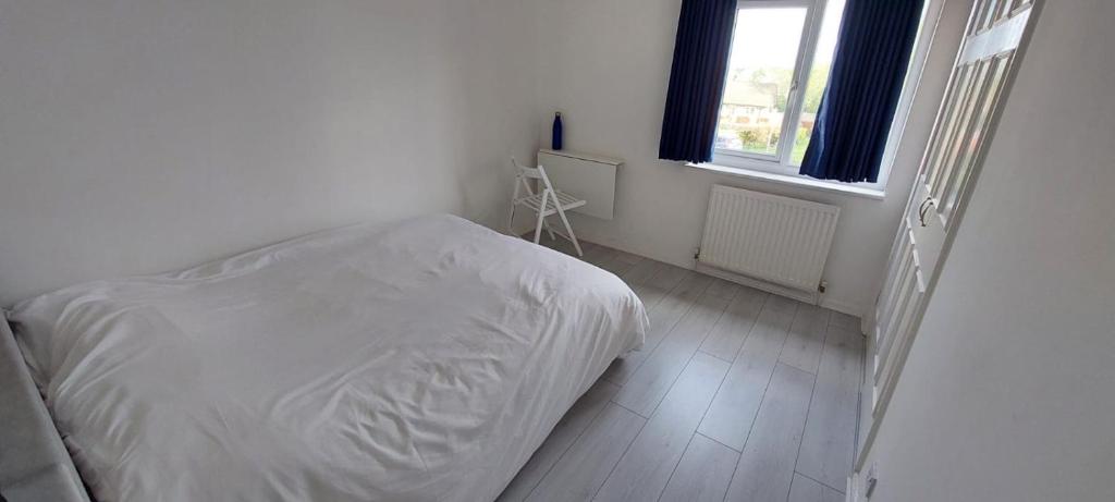 a white bedroom with a bed and a window at London Travellers Room - Romford, Hornchurch, Gidea Park to Heathrow via Elizabeth line in Harold Wood