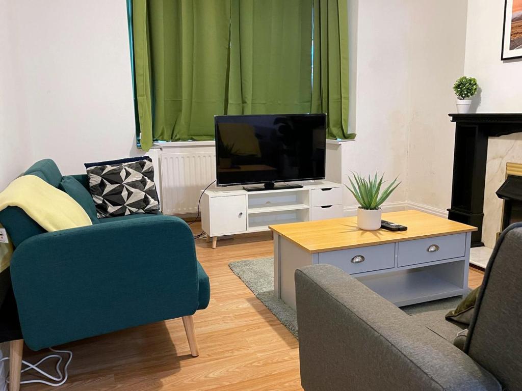 ein Wohnzimmer mit Fernseher, Couch und Tisch in der Unterkunft Lovely Spacious House Family & Contractor Friendly 3 Bedroom Near Leeds Centre Sleeps 8 in Beeston