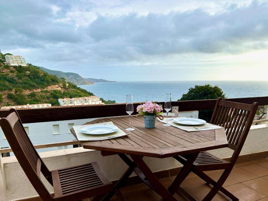 a wooden table with two chairs on a balcony with the ocean at Luxury Duplex - 2 Terraces - Private Beach in Tossa de Mar