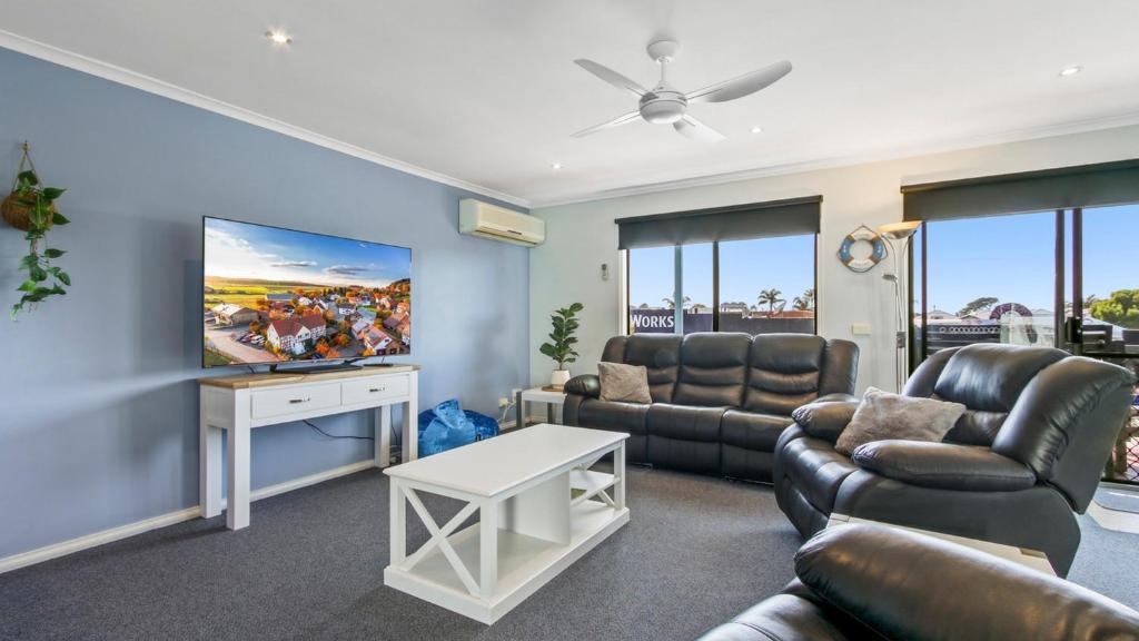 a living room with a couch and a flat screen tv at Lakes In Town - Central Getaway in Lakes Entrance