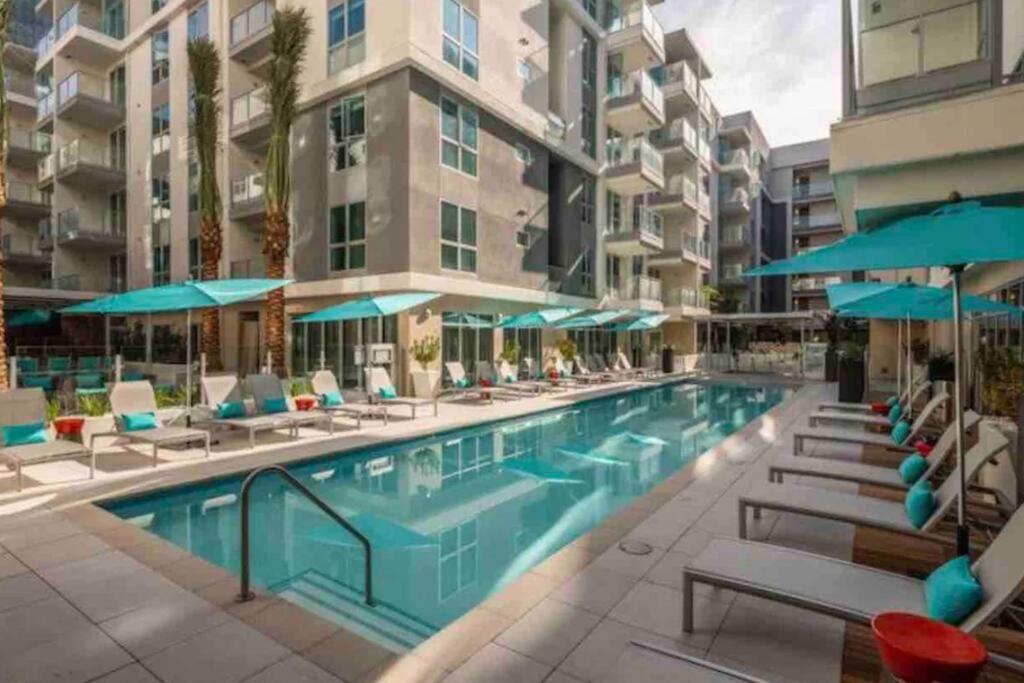 a swimming pool with chairs and umbrellas next to a building at Luxury Penthouse Loft w POOL GYM AMERICANA in Glendale