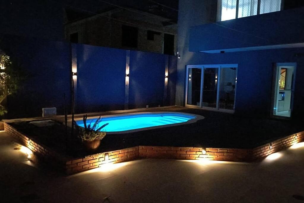 una piscina in un cortile posteriore con luci notturne di A Jóia do Cassino a Rio Grande