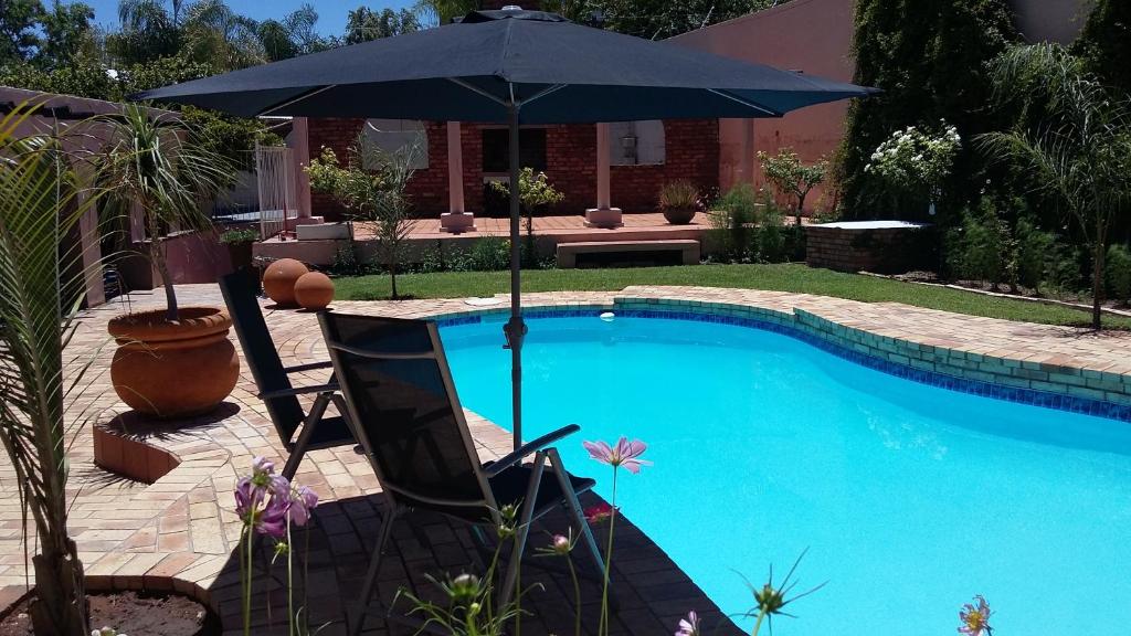 an umbrella and a chair next to a swimming pool at Stiltevrede in Upington