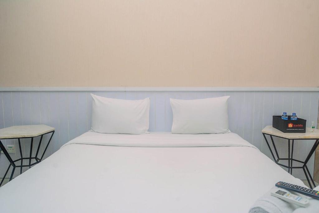 a bed with white pillows in a room at Minimalist and Comfy Studio at Grand Dhika City Apartment By Travelio in Bekasi