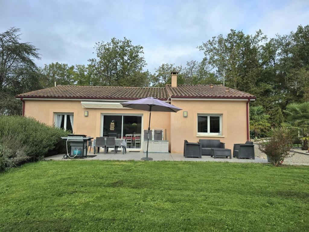 ein Haus mit einem Sonnenschirm und einem Tisch und Stühlen in der Unterkunft Belle maison plain-pied à 2 pas de Périgueux, terrasse, jardin clos, confort moderne, animaux bienvenus - FR-1-616-99 in Champcevinel