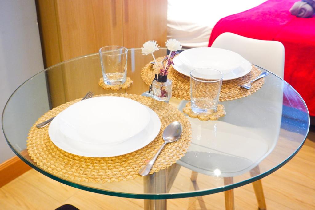 una mesa de cristal con platos blancos y cubiertos en Condo in Makati with Fast WiFi, Free Pool, Netflix and Own Balcony, en Manila