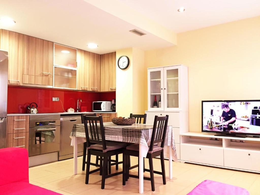 cocina con mesa con sillas y TV en Lloret Beach Apartments, en Lloret de Mar