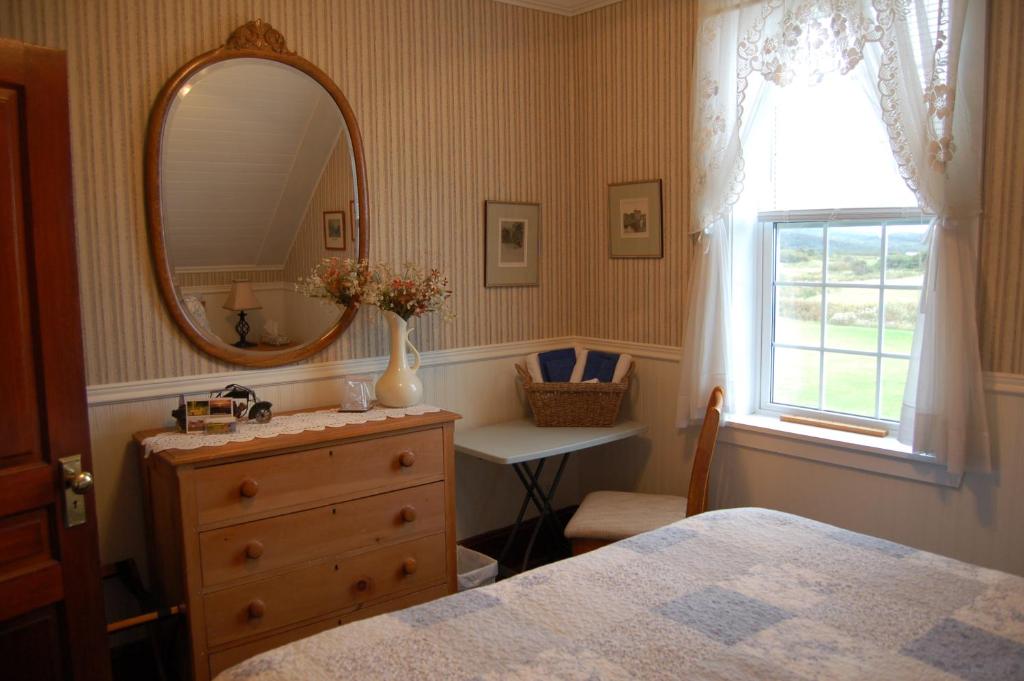 a bedroom with a mirror and a dresser and a window at The Yellow Sidecar B&B in Cap Le Moine