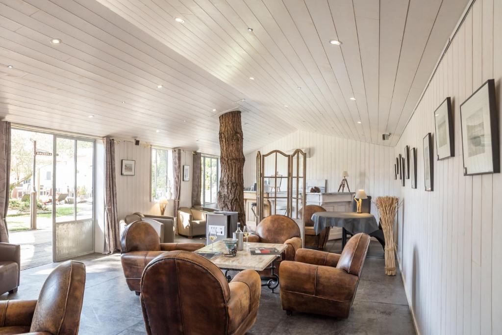 a living room with leather chairs and a table at Hôtel Restaurant & Spa Plaisir in Le Bois-Plage-en-Ré