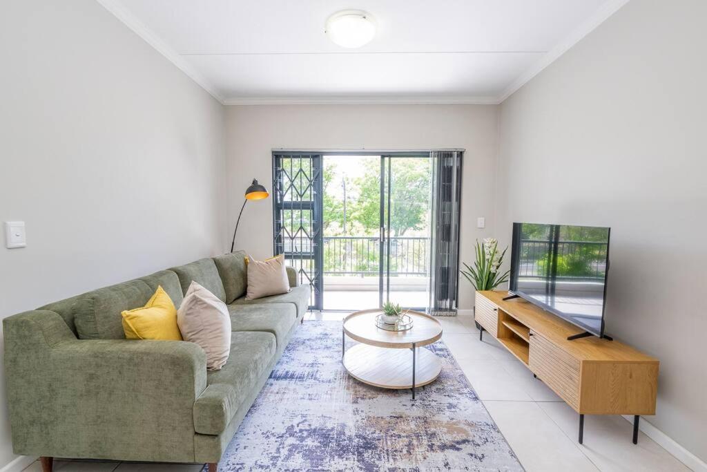 ein Wohnzimmer mit Sofa und Tisch in der Unterkunft Cozy Apartment in Brackenfell, Cape Town, ZA in Brackenfell