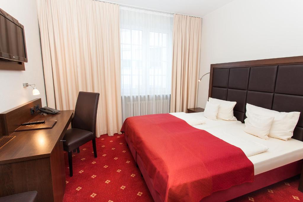 une chambre d'hôtel avec un lit et une couverture rouge dans l'établissement Centro Hotel National Frankfurt City, à Francfort-sur-le-Main