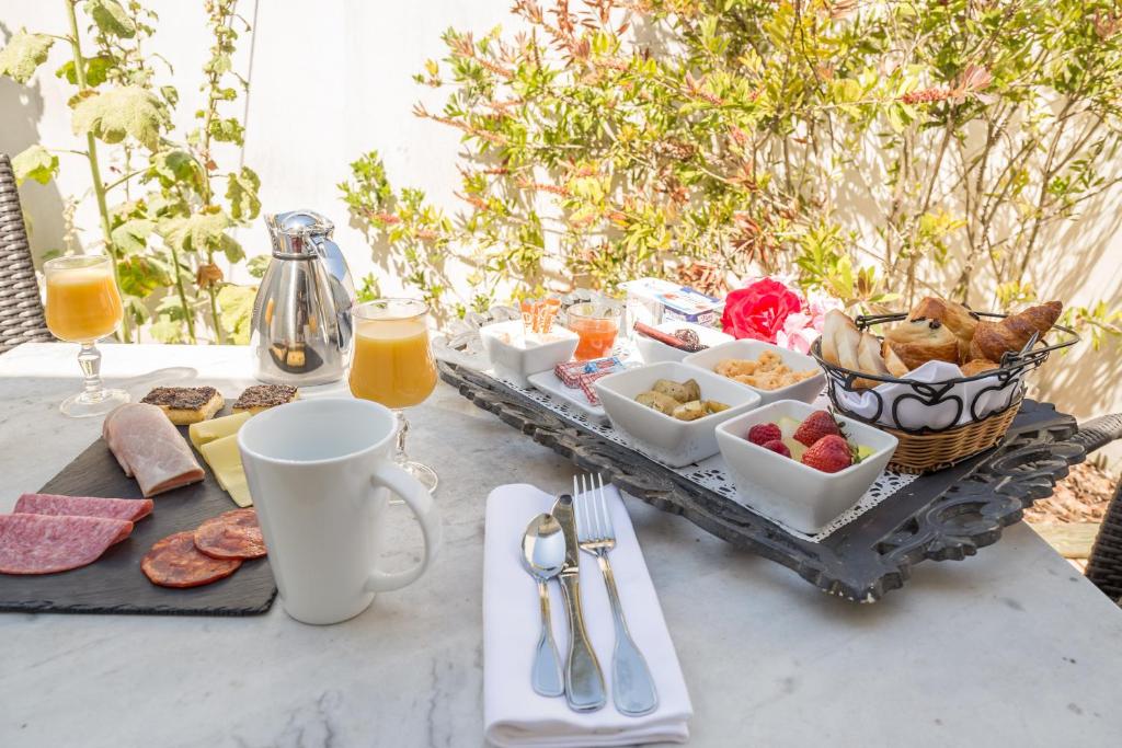 a breakfast table with a tray of food and orange juice at Hôtel Restaurant & Spa Plaisir in Le Bois-Plage-en-Ré