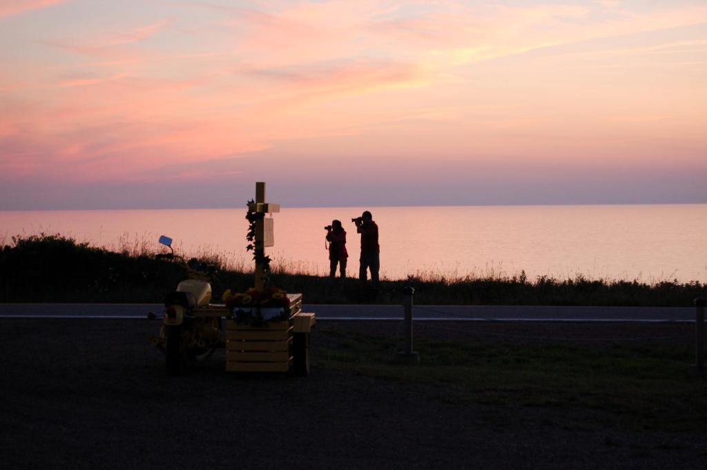 two people standing on the beach watching the sunset at The Yellow Sidecar B&B in Cap Le Moine
