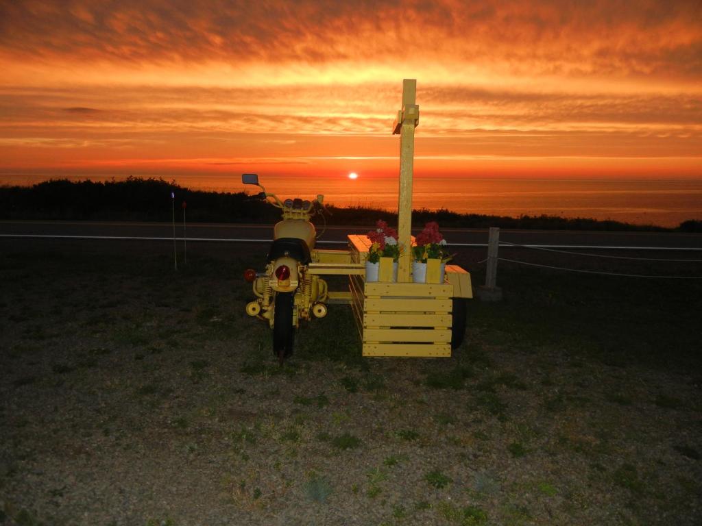 a moped parked in front of a cross with the sunset at The Yellow Sidecar B&B in Cap Le Moine