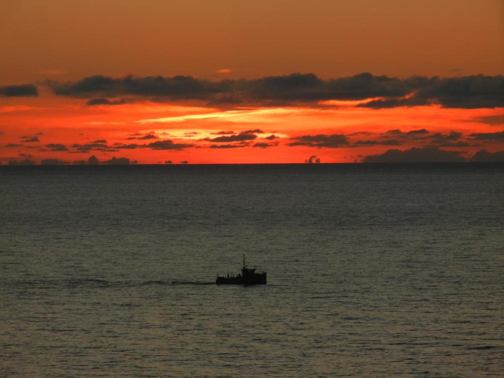 a boat in the ocean with a sunset in the background at The Yellow Sidecar B&B in Cap Le Moine