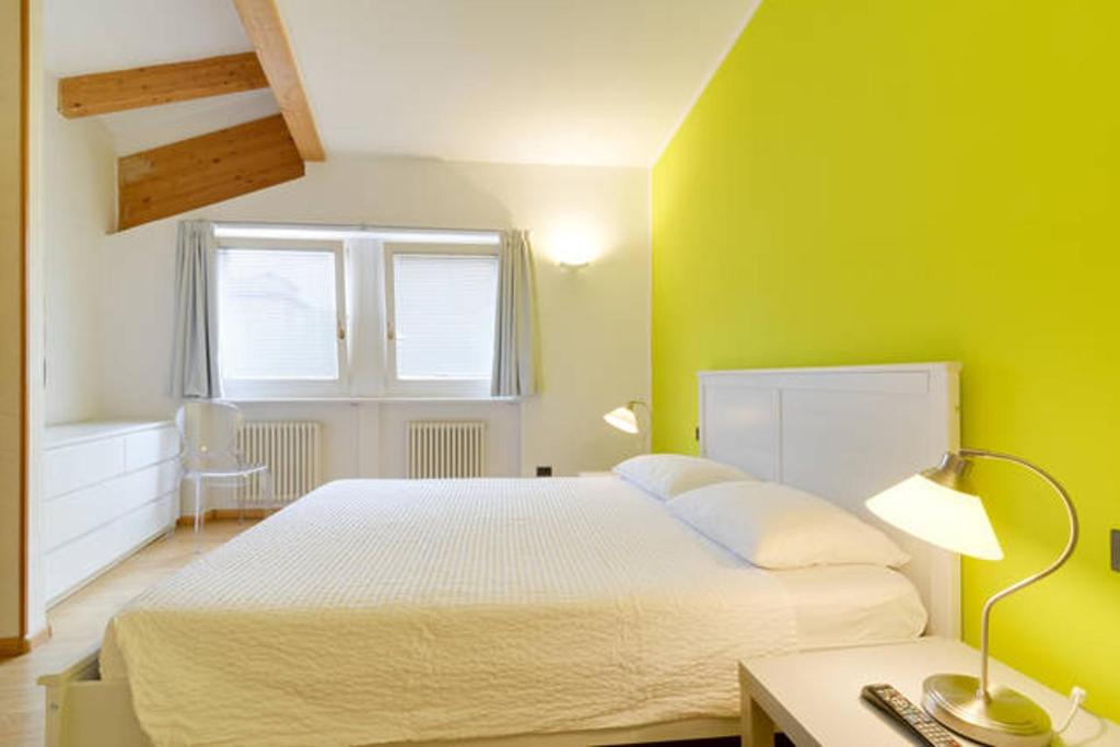 ein Schlafzimmer mit einem weißen Bett und einer grünen Wand in der Unterkunft B&B al Palazzo Malfatti in Trient