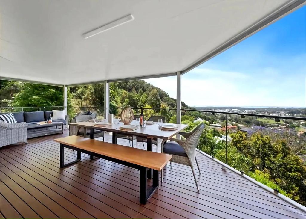 a dining table and chairs on a deck with a view at Pacific Vista in Coffs Harbour