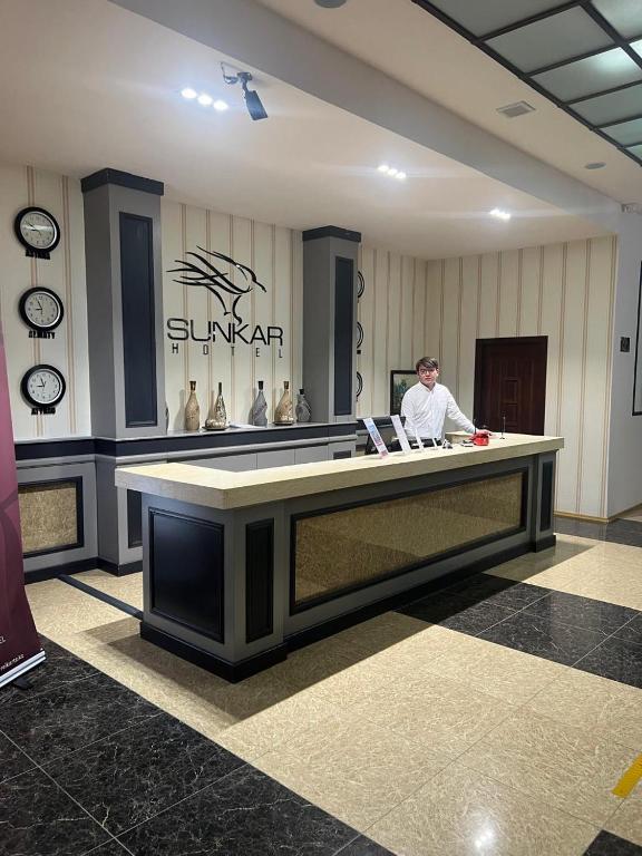 a man sitting at a reception desk in a salon at Sunkar Hotel in Atyrau