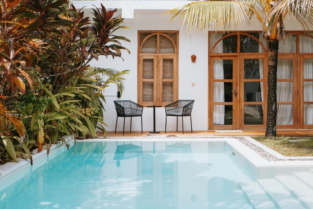 a swimming pool with two chairs next to a house at The Oasis Villa in Ahangama