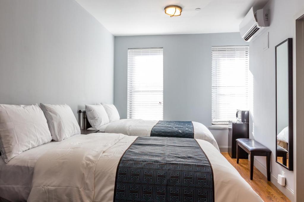 2 łóżka w sypialni z białymi ścianami i oknami w obiekcie The Park Ave North w Nowym Jorku