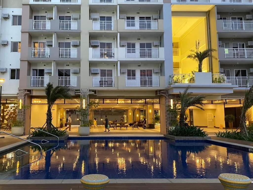 a hotel with a swimming pool in front of a building at Infina Towers in Manila