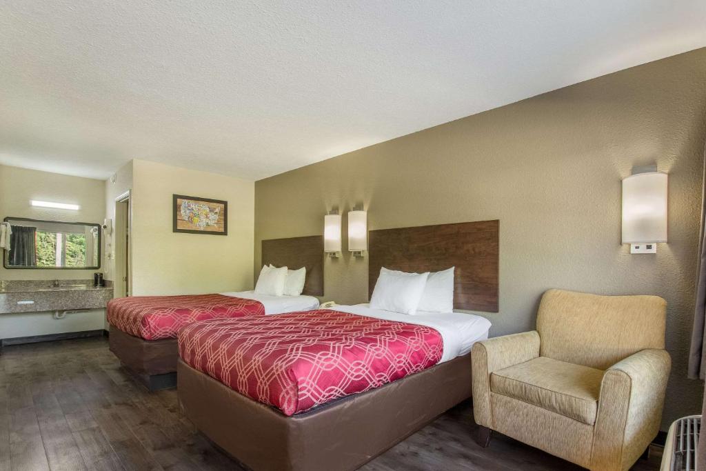 a hotel room with two beds and a chair at Econo Lodge Fort Knox in Radcliff