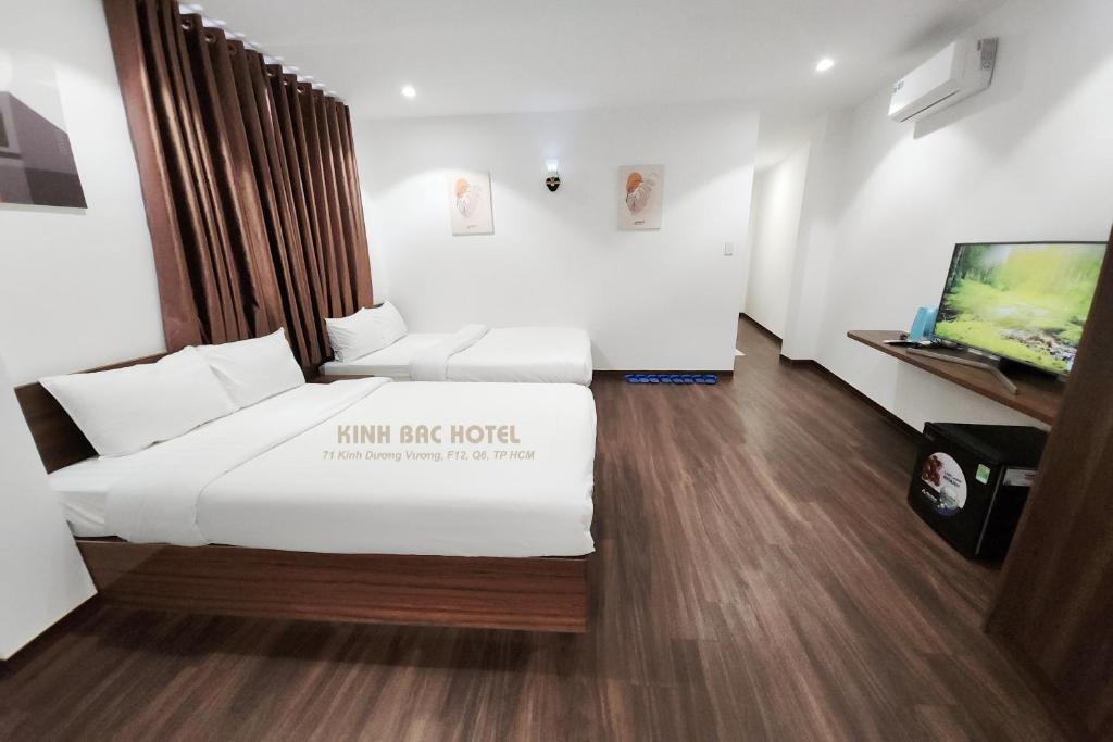 a room with two beds and a flat screen tv at Khách sạn Kinh bắc in Ho Chi Minh City