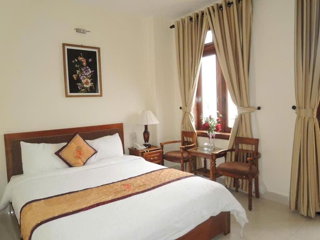 a bedroom with a bed and a desk and a window at Huyền Trang 1 Hotel Huế - by BAY LUXURY in Thôn Lại Thê